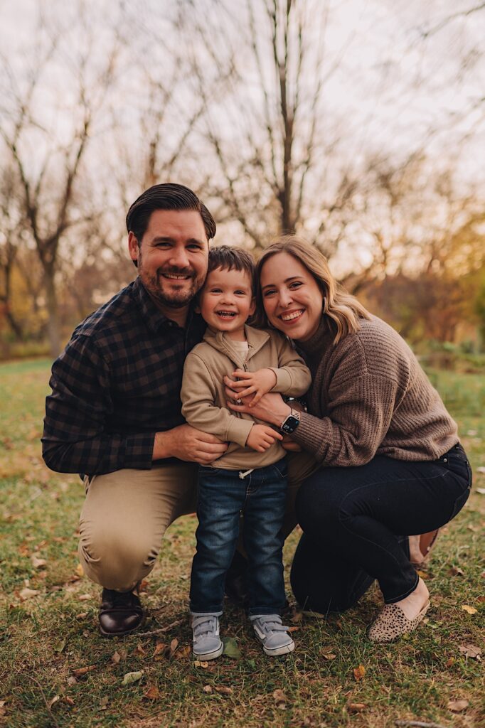 A family smiles with their child in a forest preserve in wheaton illinois.