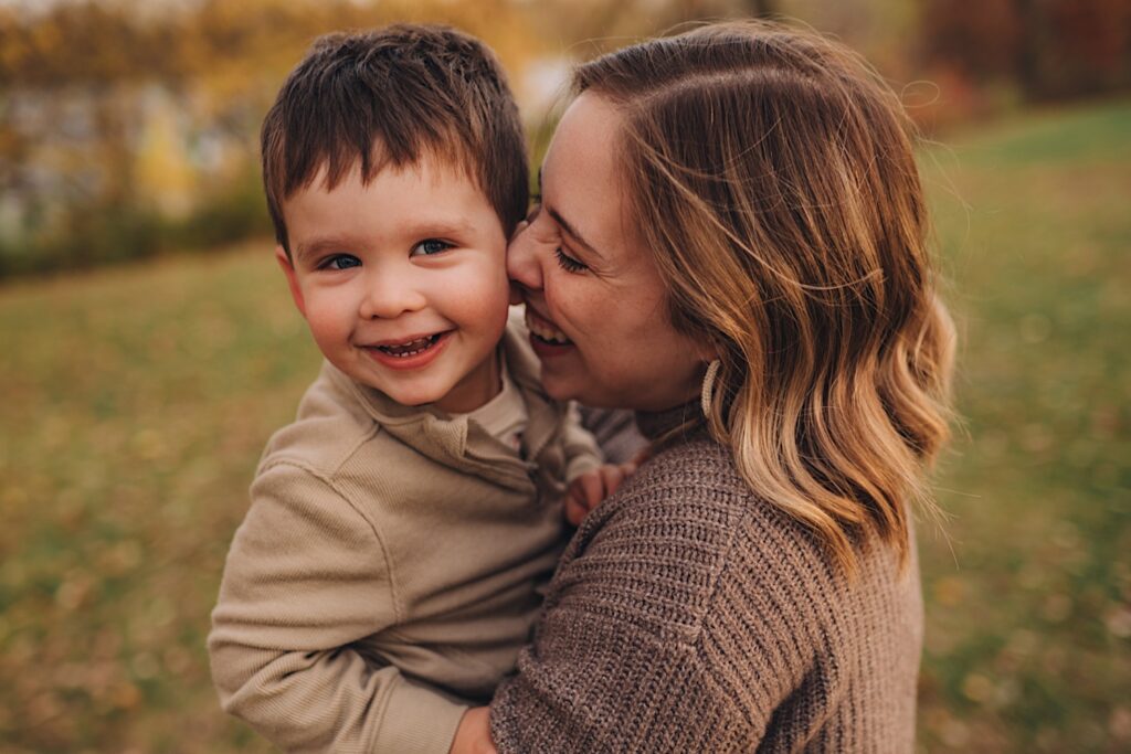 A mom holds her face close to her sons and laughs while posing for a photo at a forest preserve in wheaton illinois