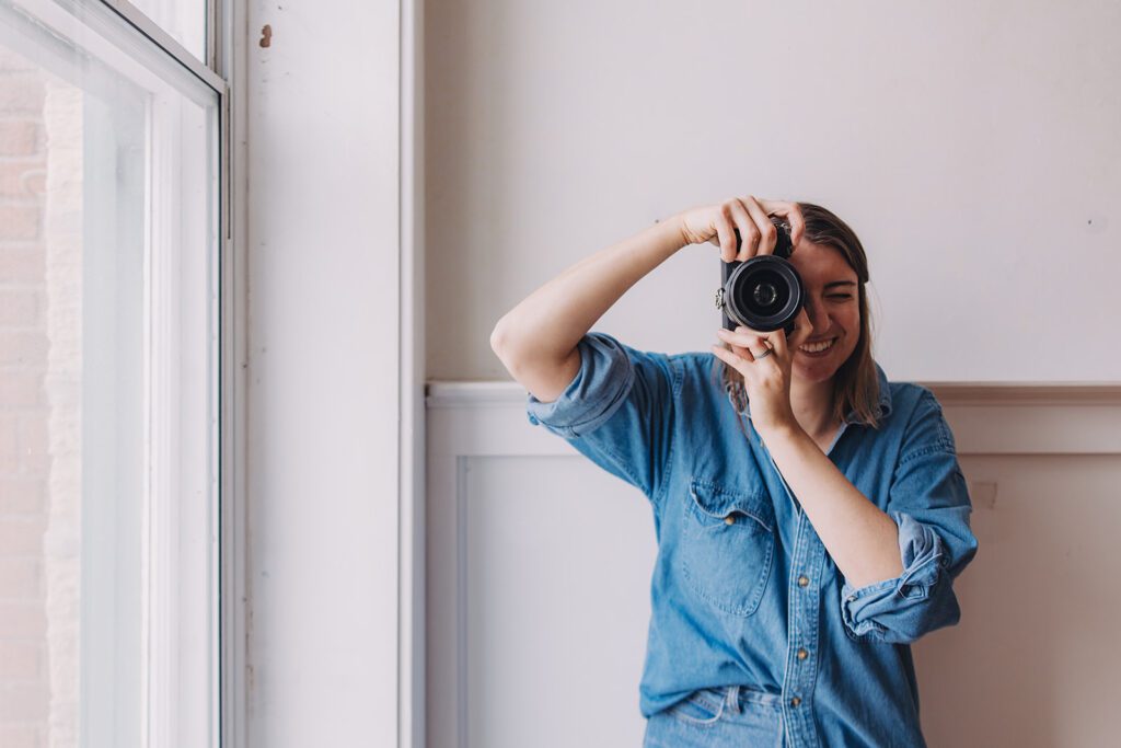 Marisa of Marisasav standing holding her camera which she uses to photograph weddings.